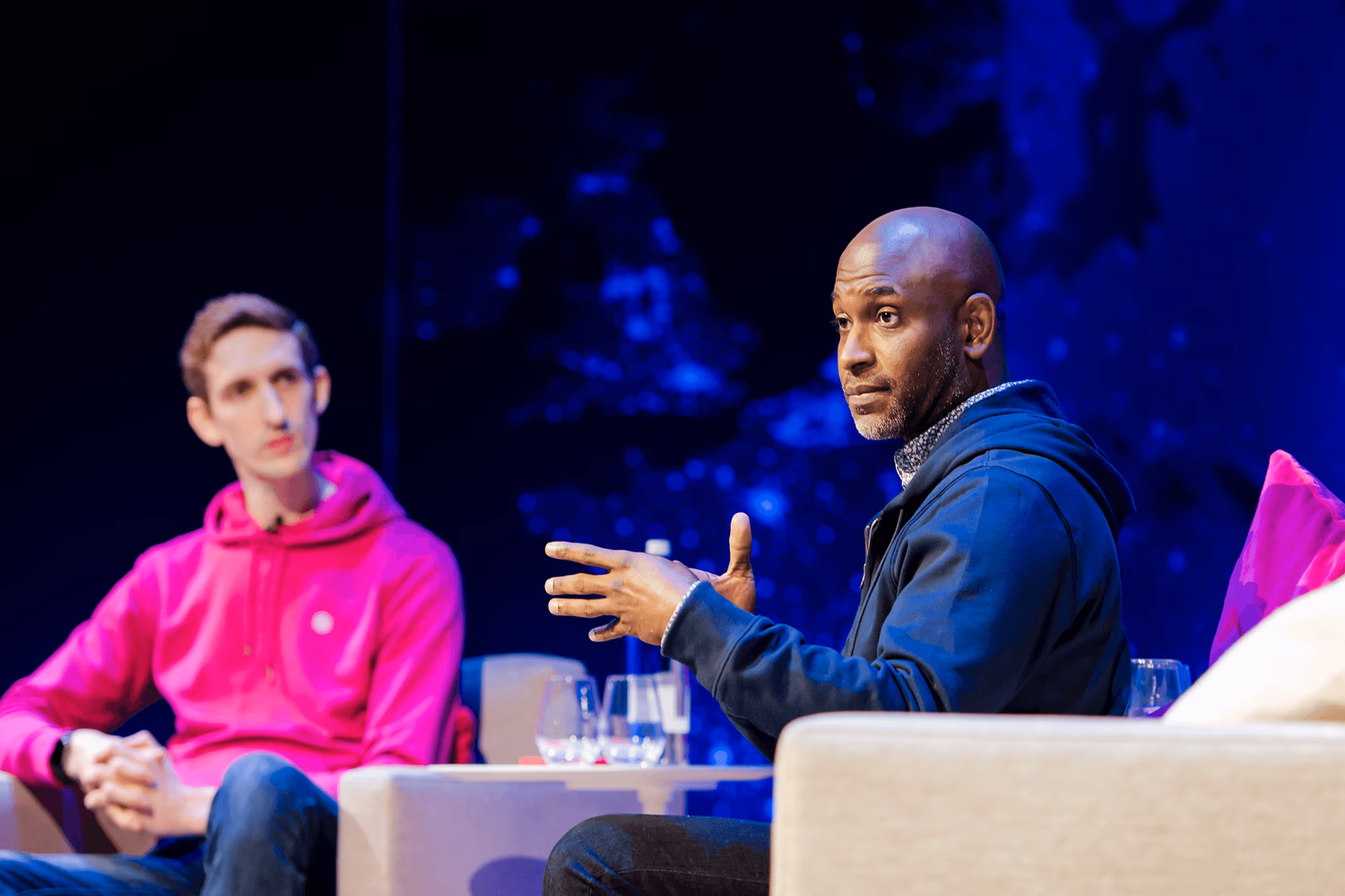Two speakers in armchairs on stage during a panel discussion